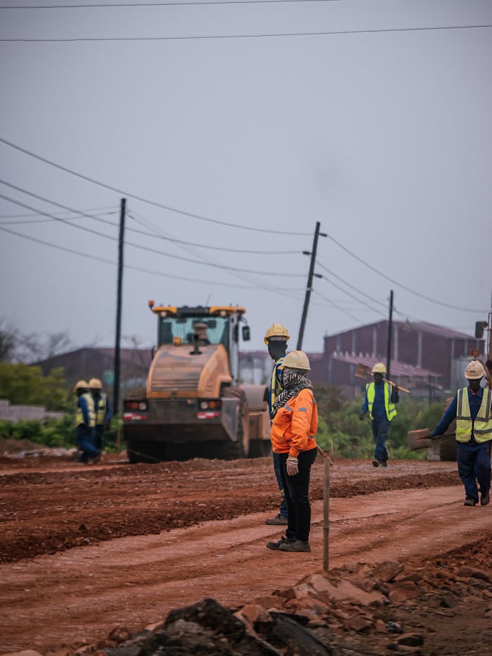 services-03 Construction workers at a road site operating heavy machinery, ensuring safety standards.