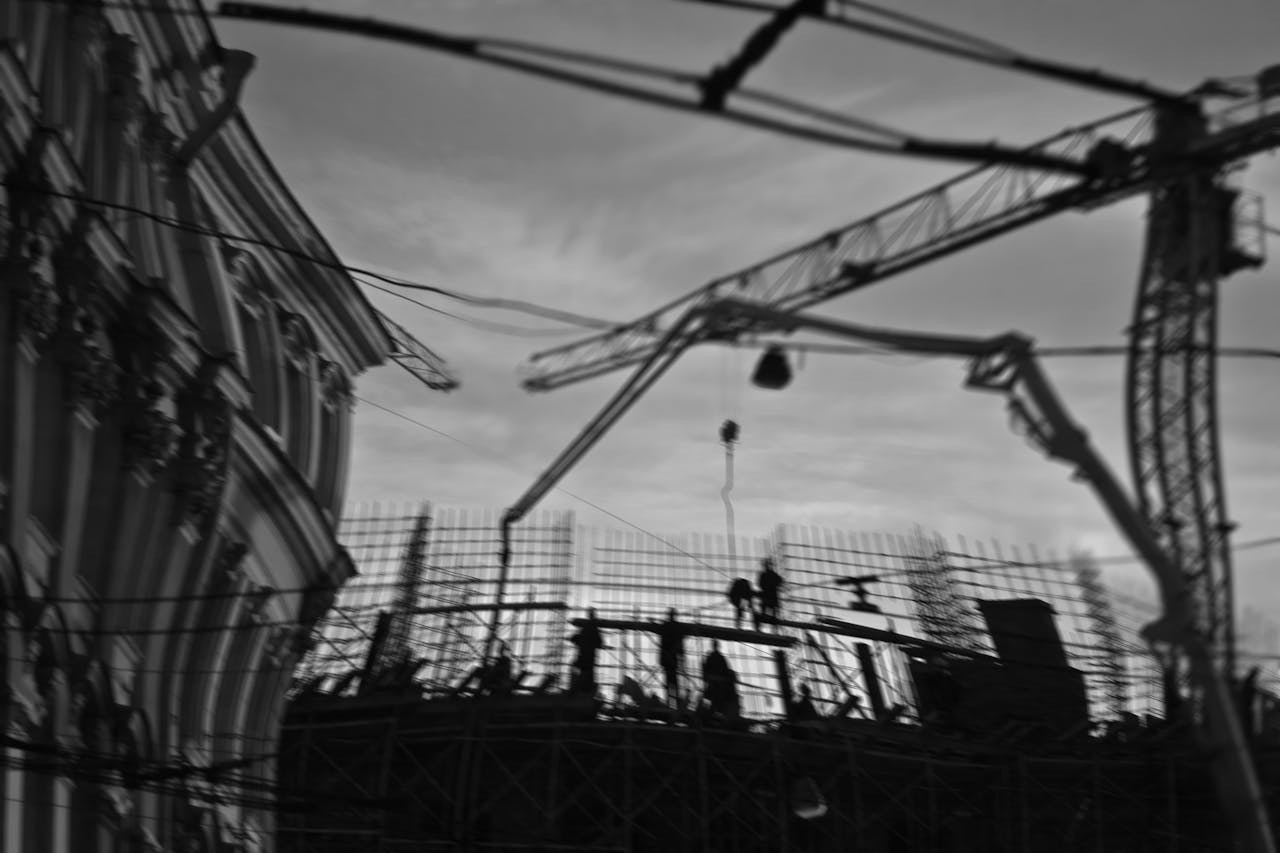 From below black and white of builders on construction site near tall crane and building